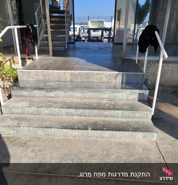 מעקה מתכת לבן ליד מדרגות בטון
